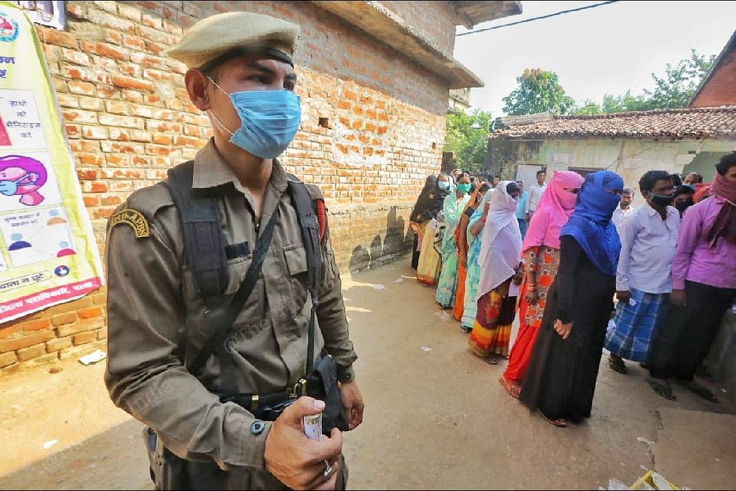A police personnel wearing masks stands at the polling booth in Maharajpur village | Praveen Jain | ThePrint 