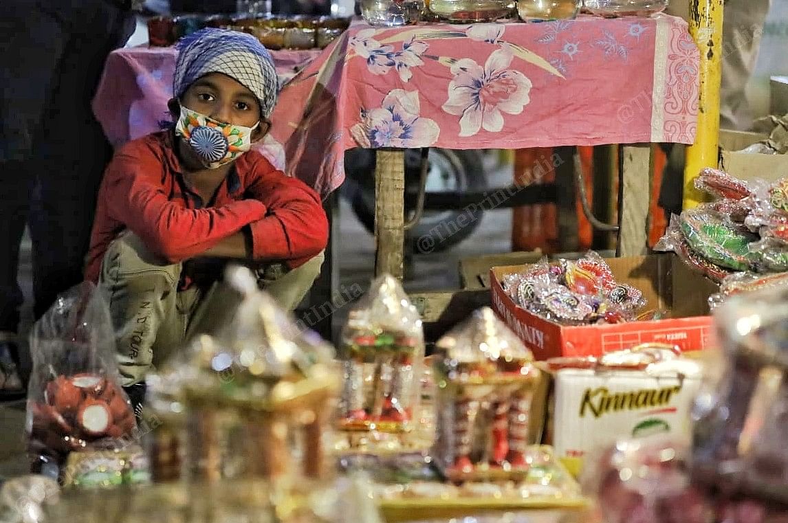 A kid sits at a shop in Amar Colony market | Photo: Manisha Mondal | ThePrint