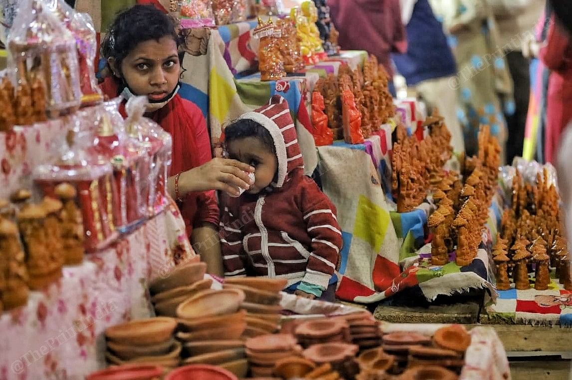 A mother feeds a toddler at a market | Photo: Manisha Mondal | ThePrint