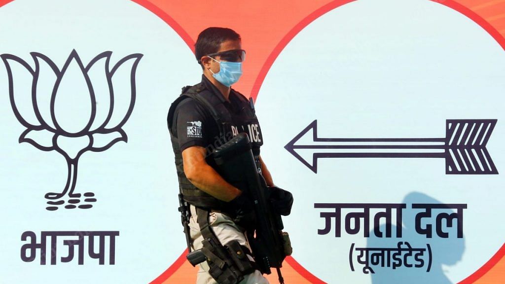 A Special Protection Group personnel stands between the party banners of BJP and JD(U) | Photo: Praveen Jain | ThePrint