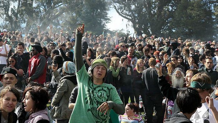 A cloud of smoke rests over the heads of a group of people during a 420 Day celebration on 