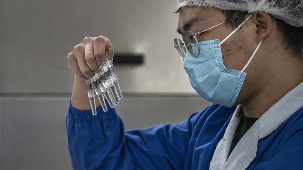 A worker checks syringes of a potential vaccine CoronaVac on the production line at Sinovac Biotech in Beijing on 24 September