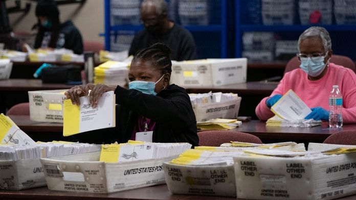 Election officials wearing protective masks sort empty absentee ballot envelopes for the 2020 US election in Decatur, Georgia on 5 November