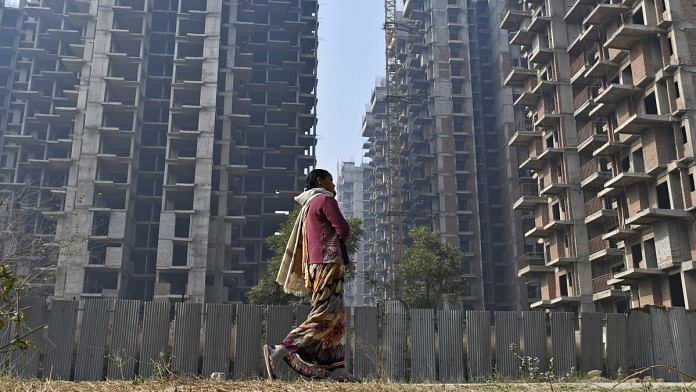 File image of a woman walking past buildings under construction in Noida, Uttar Pradesh | Photo: Anindito Mukherjee/Bloomberg