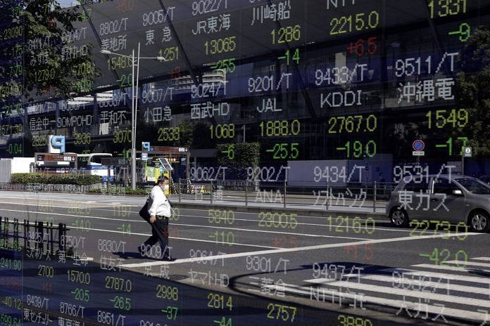 A pedestrian wearing a protective face mask is reflected in an electronic stock board outside a securities firm in Tokyo, Japan on 29 October, 2020| Photographer: Kiyoshi Ota/Bloomberg
