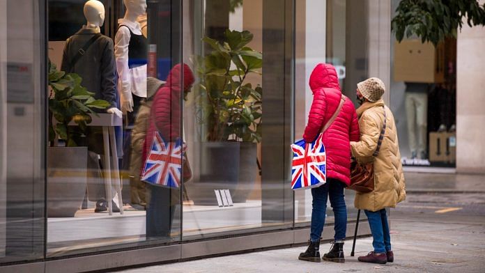 A shopper holding a carrier bag with a Union Flag in front of a store in London