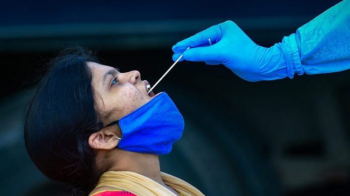 A health worker collects swab sample of a passenger for Covid-19 test at the KSRTC bus stand in Bengaluru, Monday, Dec. 14, 2020. | PTI