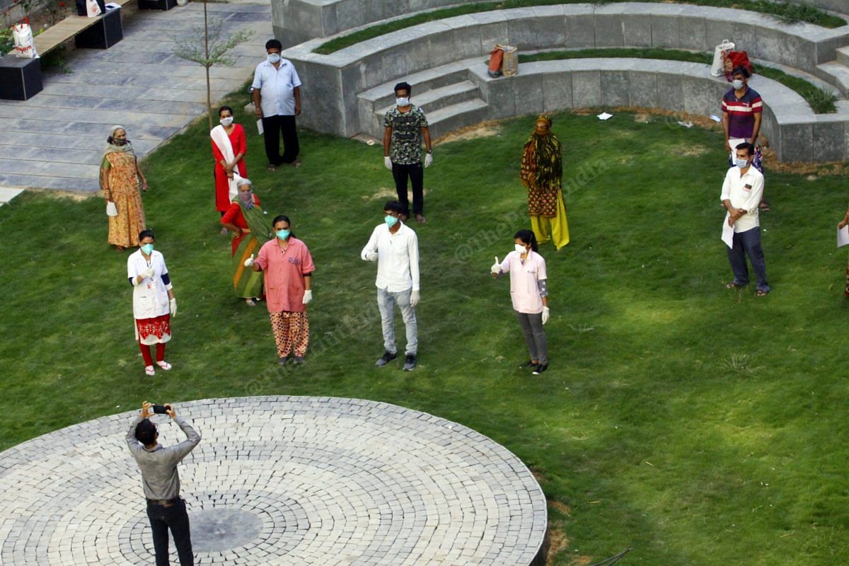 People who recovered from Covid-19 stand for a group photograph, albeit with social distancing, in the lawn of the quarantine centre at Vadodara | Praveen Jain | ThePrint