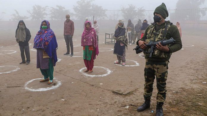 Voters, maintaining social distancing, stand in queues as they wait to cast their votes for the last phase of District Development Council elections, at Pragwal village in Jammu, Saturday, Dec. 19, 2020. | PTI