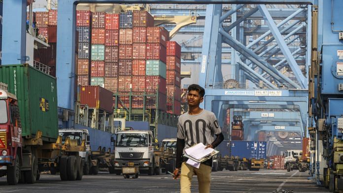 An employee walks past gantry cranes loading shipping containers onto trucks from the Cosco New York container ship docked at the Jawaharlal Nehru Port, operated by JNPT, in Navi Mumbai. Photographer: Dhiraj Singh | Bloomberg