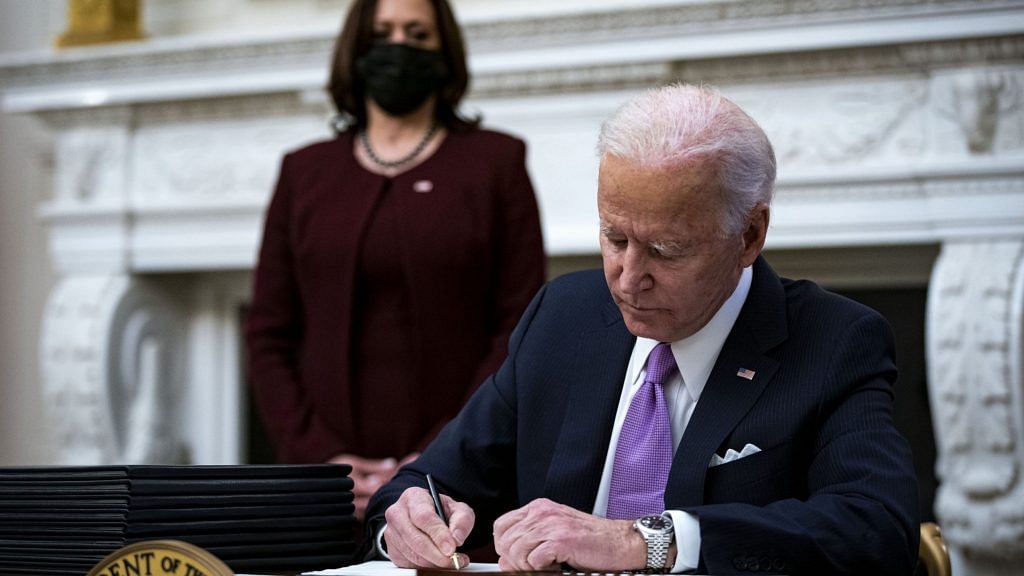 US President Joe Biden signs an executive order after speaking during an event on his administration's Covid-19 response as Vice President Kamala Harris looks on. | Photographer: Al Drago | Bloomberg