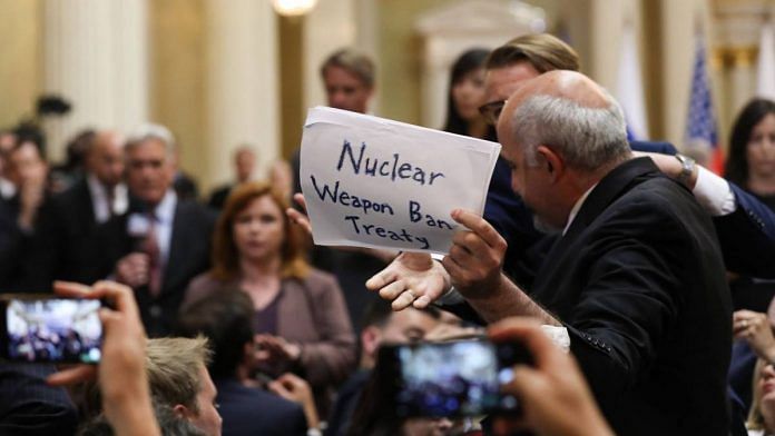 Security removes a protester as he holds a handwritten sign reading 'Nuclear weapon ban treaty' in Helsinki, Finland, in July 2018 | Chris Ratcliffe | Bloomberg