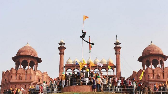 A protester hoists the Nishan Sahib at the Red Fort in Delhi on 26 January | ThePrint Photo | Manisha Mondal