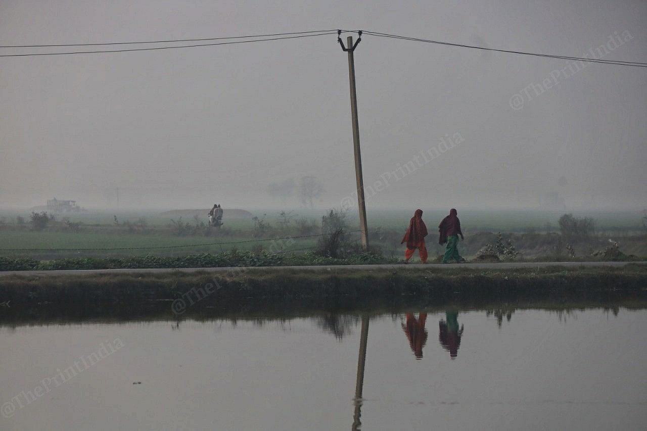 Women pass by a water body in Rugsana village | Manisha Mondal | ThePrint