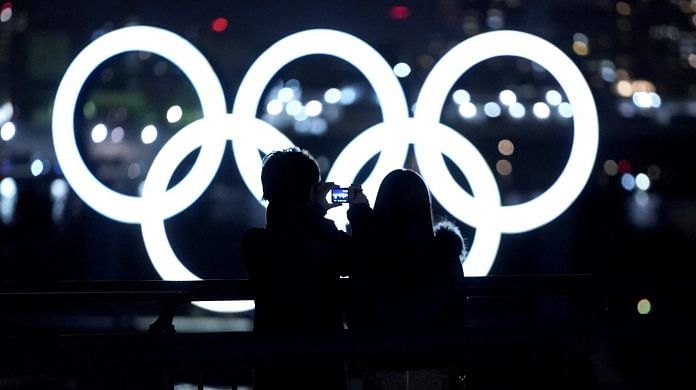 A visitor takes a photograph of illuminated Olympic rings floating in the waters off Odaiba island in Tokyo, Japan on 14 January | Photo: Toru Hanai | Bloomberg