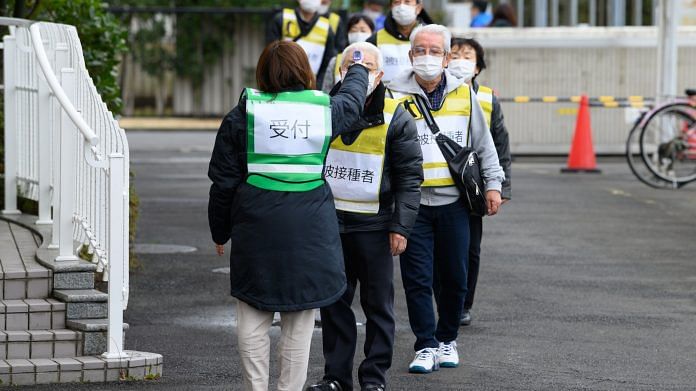 Volunteers line up to get their temperatures taken during a vaccination simulation in Kawasaki, Kanagawa Prefecture, Japan, on 27 January 2021