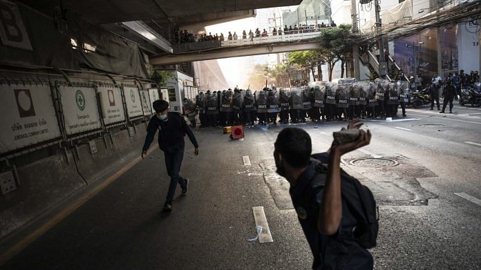 A demonstrator prepares to throw a rock towards riot police during a protest outside the Embassy of Myanmar in Bangkok, Thailand, on Monday, Feb. 1 2021. | Photographer: Andre Malerba | Bloomberg