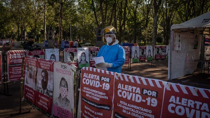 A medical worker wearing personal protective equipment stands at a temporary Covid-19 testing kiosk in Mexico City | Photographer: Alejandro Cegarra | Bloomberg