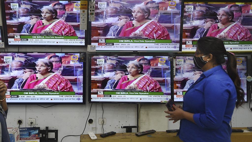A woman watches Finance Minister Nirmala Sitharaman presenting Union Budget 2021-21 on television sets, at an electronics store in Kolkata | PTI Photo