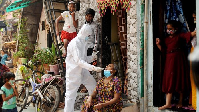 A BMC health worker in protective gear takes a swab sample of a woman for Covid test at Dharavi in Mumbai, on 23 February 2021 | ANI Photo