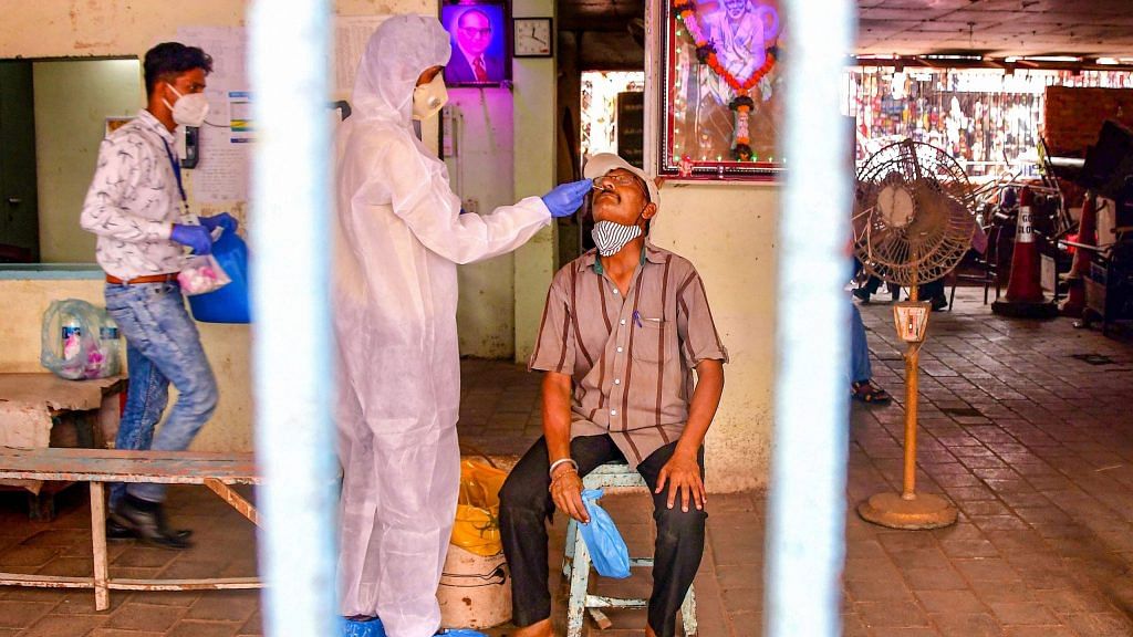 A heath worker, wearing PPE, conducts COVID-19 testing of a man at Dadar market in Mumbai on 22 March, 2021 | PTI