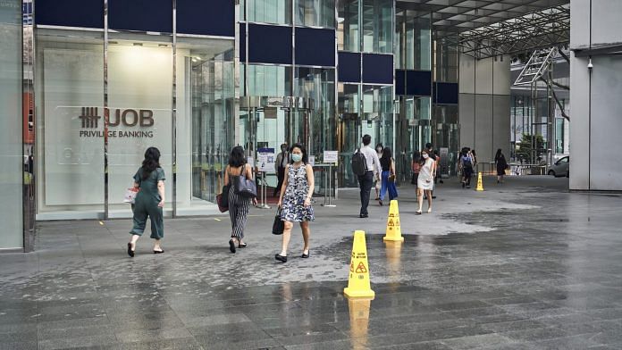 Pedestrians walk past a United Overseas Bank Ltd. (UOB) branch in the central business district in Singapore | Photographer: Lauryn Ishak | Bloomberg