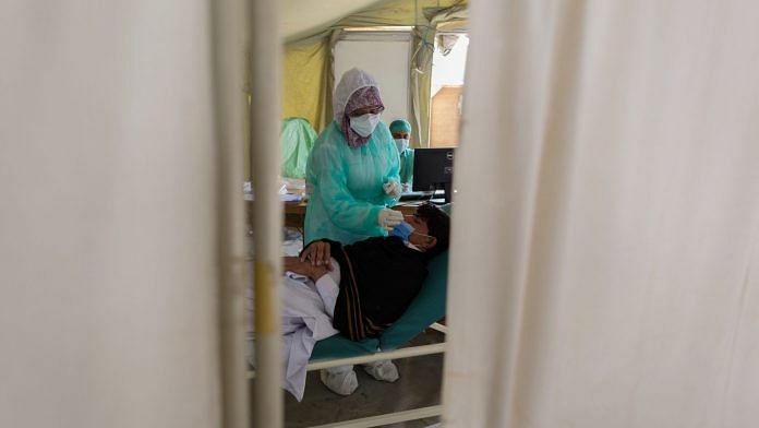 A health worker collects a swab from a person at a Covid-19 testing facility set-up at the Indus Hospital in Karachi on 28 January, 2021| Asim Hafeez | Bloomberg