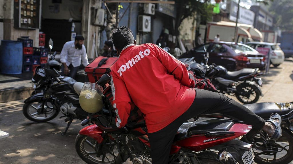 A food delivery rider for Zomato Media Pvt. gets on a motorcycle as he waits for an order outside of a restaurant in Mumbai, India, on Tuesday, Jan 21, 2020. Uber Technologies Inc. will sell Uber Eats in India to local rival Zomato in a $172 million deal, according to a person familiar with the transaction, underscoring the ride-hailing giants effort to cut back on loss-making operations. Photographer: Dhiraj Singh/Bloomberg