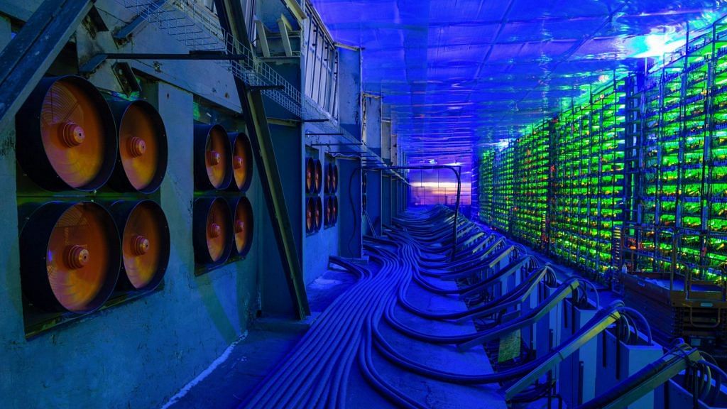 Industrial cooling fans operate to thermally regulate illuminated mining rigs at the CryptoUniverse cryptocurrency mining farm in Nadvoitsy, Russia | Representational Image | Photographer: Andrey Rudakov | Bloomberg