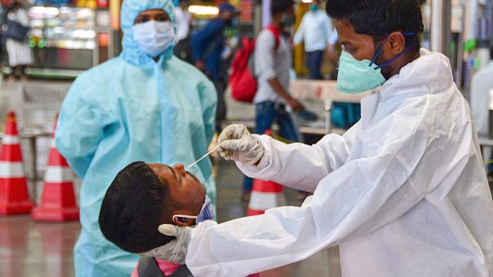 A health worker takes a nasal swab sample of a passenger for coronavirus tests at the CSMT railway station, owing to surge in COVID-19 cases in Mumbai, Friday, Feb. 26, 2021. | PTI
