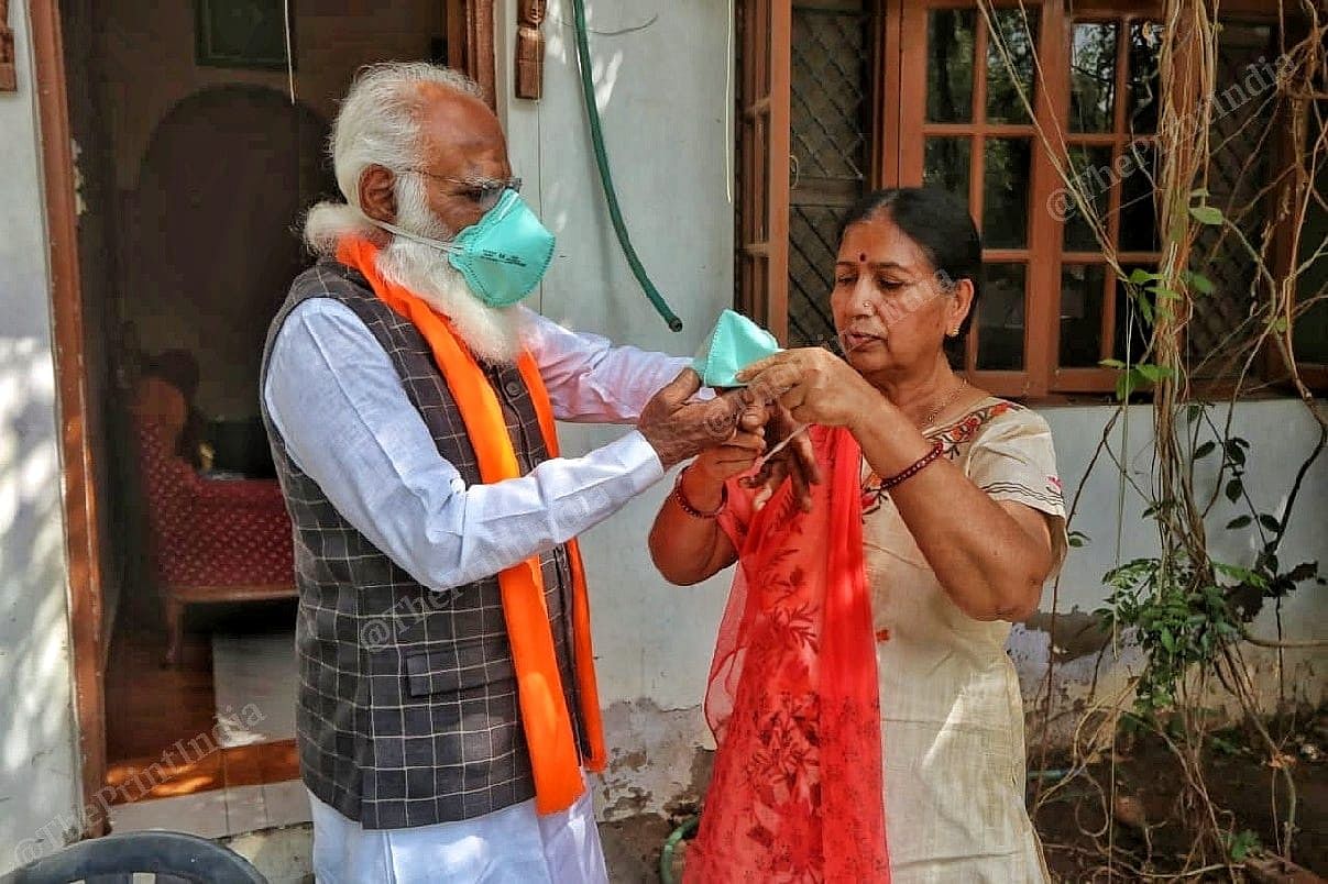 Lalji Devaria helping his wife Bharti to wear the mask before leaving for market | Photo: Praveen Jain | ThePrint