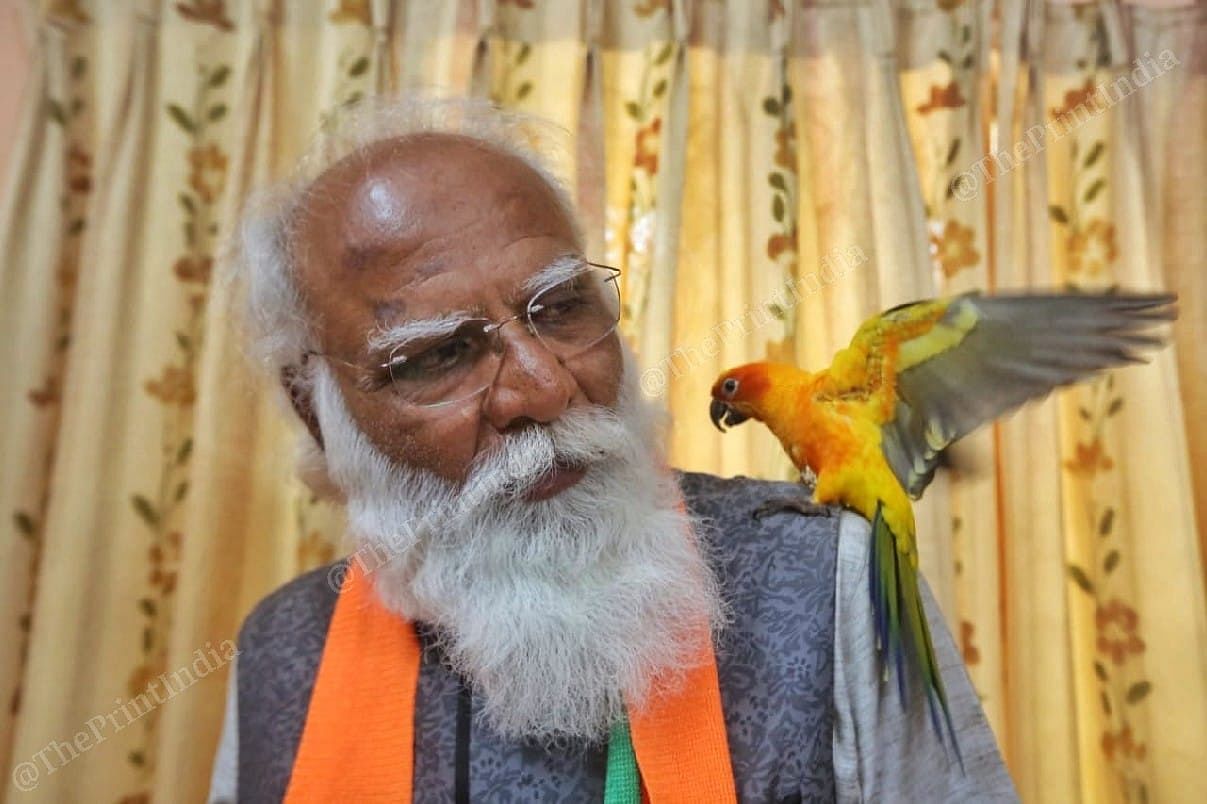 Lalji Devaria looking at his at his pet parrot Mango | Photo: Praveen Jain | ThePrint