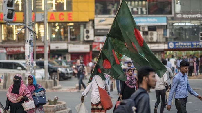 A street vendor carries Bangladeshi national flags in Dhaka, Bangladesh