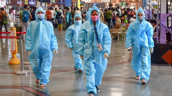 Health workers wearing PPE kits walk on a platform at CSMT, in Mumbai on 24 March, 2021 | PTI