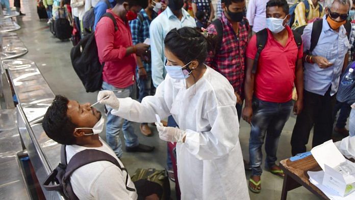 A health worker collects swab samples of a passenger at CSMT station in Mumbai for a Covid test | Photo: PTI