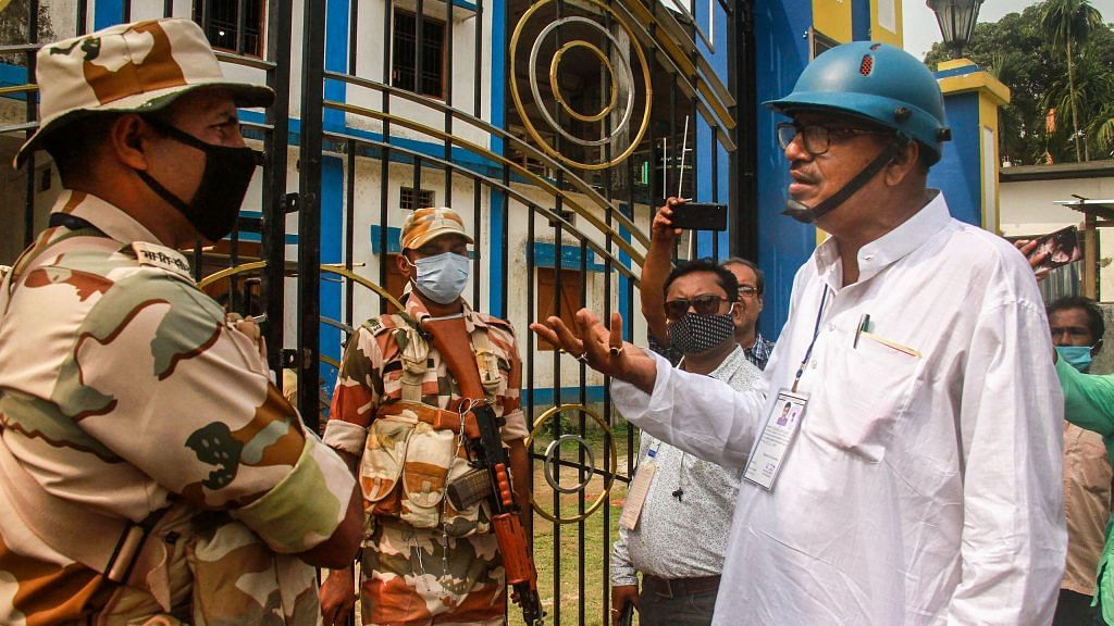 TMC candidate Rabindra Nath Ghosh, wearing a helmet for safety, interacts with security personnel during 4th phase of West Bengal polls, in Cooch Behar | PTI