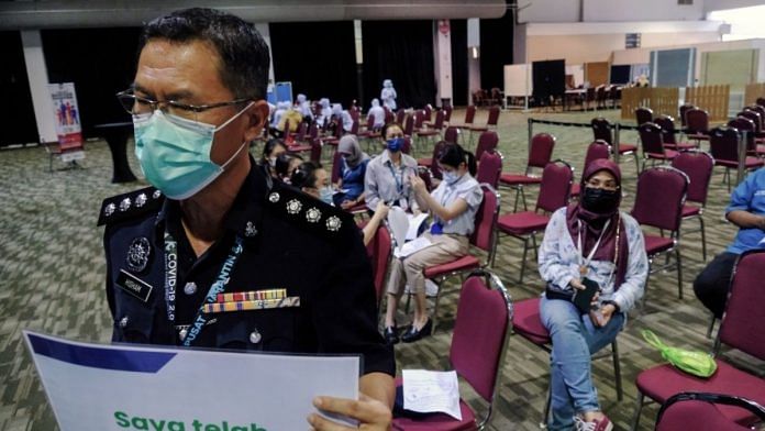 A police office holds up a placard after taking the Pfizer-BioNTech Covid-19 vaccine at the Malaysia Agro Exposition Park Serdang (MAEPS) vaccination center in Serdang, Selangor, on 4 March 2021 | Samsul Said | Bloomberg
