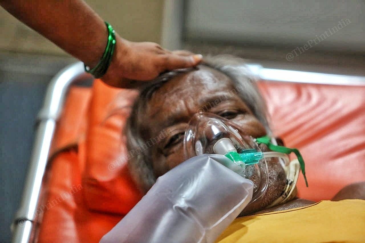A family member keeps hand on the head of a patient | Photo: Praveen Jain | ThePrint