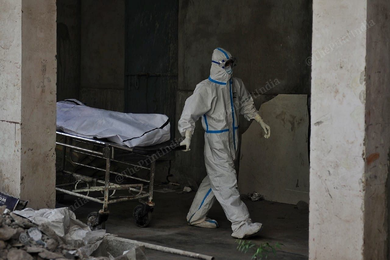 A healthcare worker transports the body of a deceased Covid patient on a gurney for transportation| Photo: Suraj Singh Bisht | ThePrint