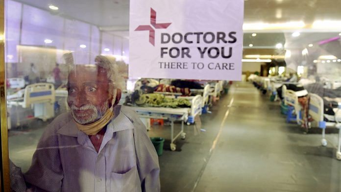 A Covid patient looks at his family through a glass barrier at Shehnai Banquet Hall, temporarily converted into an isolation ward near LNJP Hospital in New Delhi