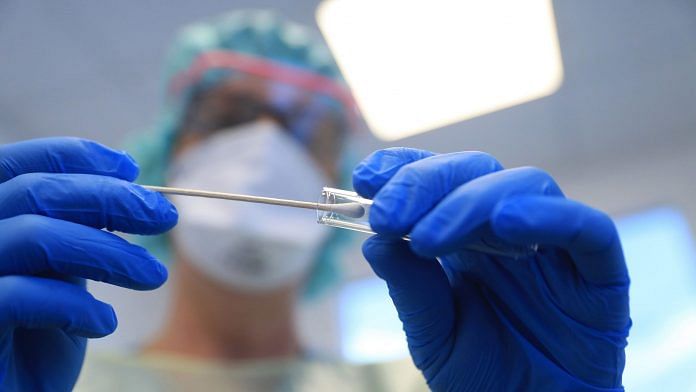 Representational image | A doctor wearing personal protective equipment (PPE) places a saliva swab into a test tube for analysis during coronavirus symptom tests in Germany | Photographer: Krisztian Bocsi | Bloomberg