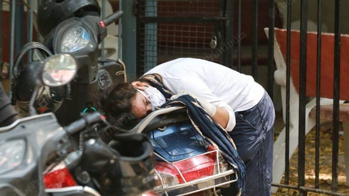 A woman rests her head on the seat of a scooter as she weeps outside a Delhi mortuary while waiting for the body of her sister, who died of Covid-19 Thursday | Manisha Mondal | ThePrint