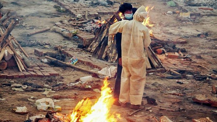 Family members stand between burning pyres at the Seemapuri crematorium | Praveen Jain | ThePrint