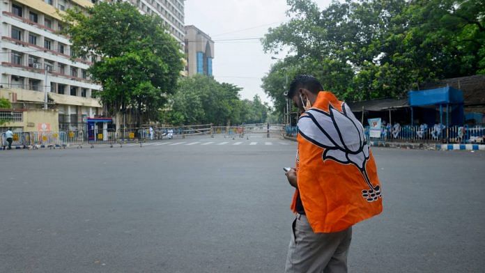 A BJP supporter wears the party flag during the election result day of the West Bengal Assembly election, in Kolkata Sunday | ANI