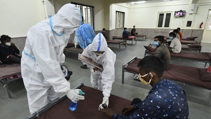 Health workers sanitize a patient receiving treatment at a Covid care centre in New Delhi