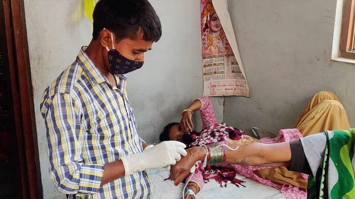 Kapoori Kumar inserts a Peripheral IV into a patient's hand in Bampali village, Arrah | Sajid Ali | ThePrint