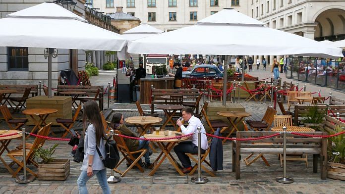 People sit at outdoor dining tables set up outside a restaurant at Covent Garden in London, on 11 May 2021
