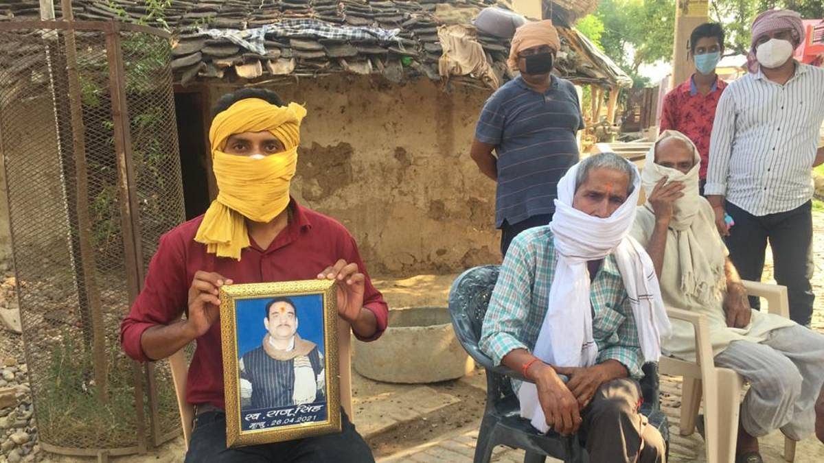 Ram Narayan Singh’s cousin (in red shirt) holds his photo. Singh, died on 26 April after suffering from fever and shortness of breath | Moushumi Das Gupta | ThePrint