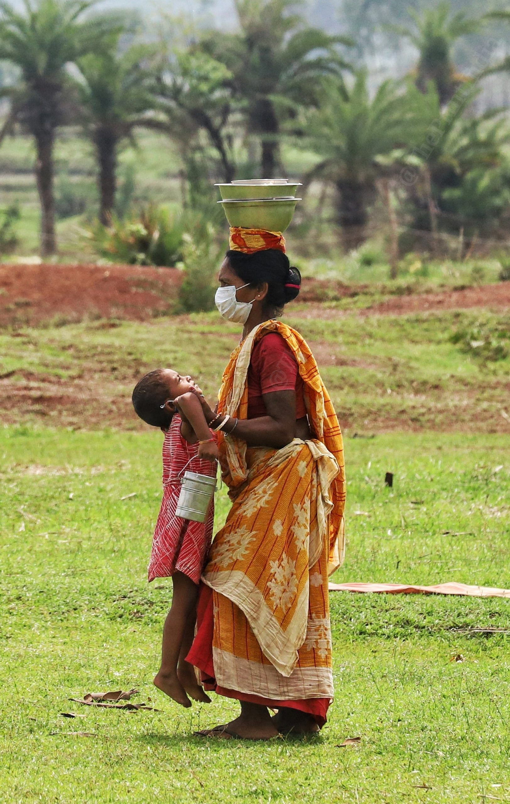 A woman carries the tiffin on her head and her daughter in her arms | Photo: Manisha Mondal | ThePrint