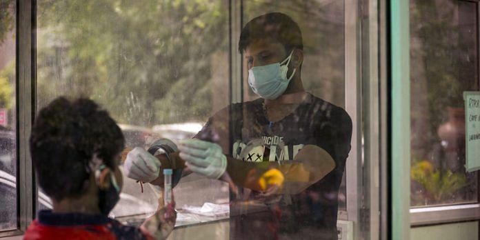 A health worker takes a swab sample at a Covid-19 testing site at a district hospital in Noida, Uttar Pradesh | Photographer: Anindito Mukherjee | Bloomberg